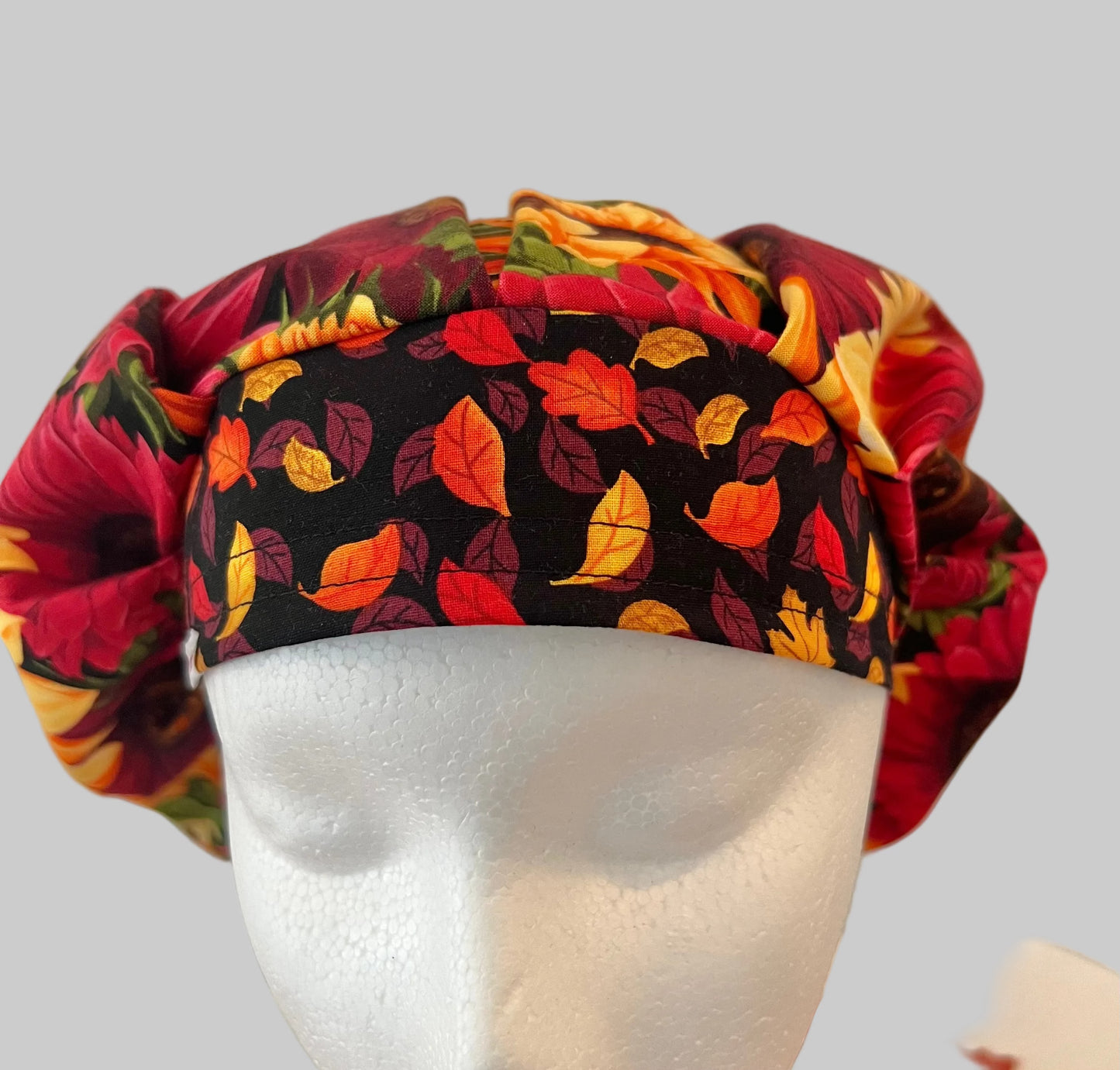 Top view of red & gold sunflower fall bouffant scrub cap fabric — handmade USA autumn surgical hat for OR nurses with room for long hair.