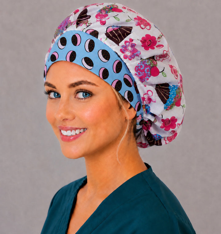 Woman wearing the retro cupcake bouffant scrub cap, left side view — pink floral cupcake print with a blue ice cream sandwich contrast band, adjustable women&