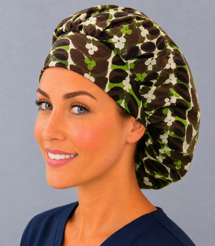 Retro leaf bouffant scrub cap, left angled view — chocolate brown leaves with green and cream clover blossoms, roomy adjustable surgical hat for women