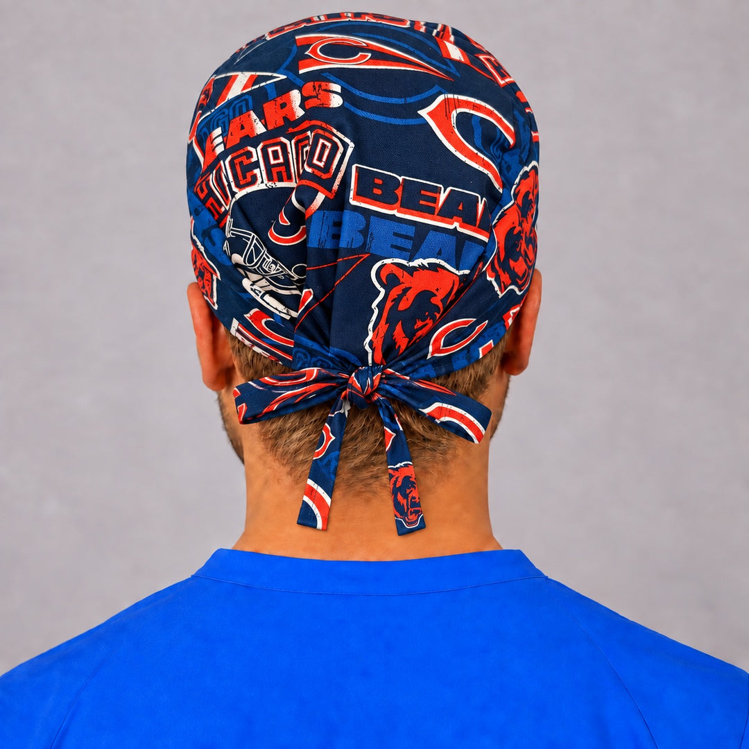 Right three-quarter view of a retro navy and orange football surgical hat for men, showing distressed helmet and pennant graphics across the side panel and a short tied bow