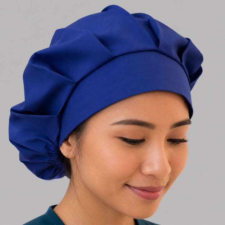 Royal blue bouffant scrub cap right downward angle showing thick band and gathered solid royal blue crown, OR World surgical hat