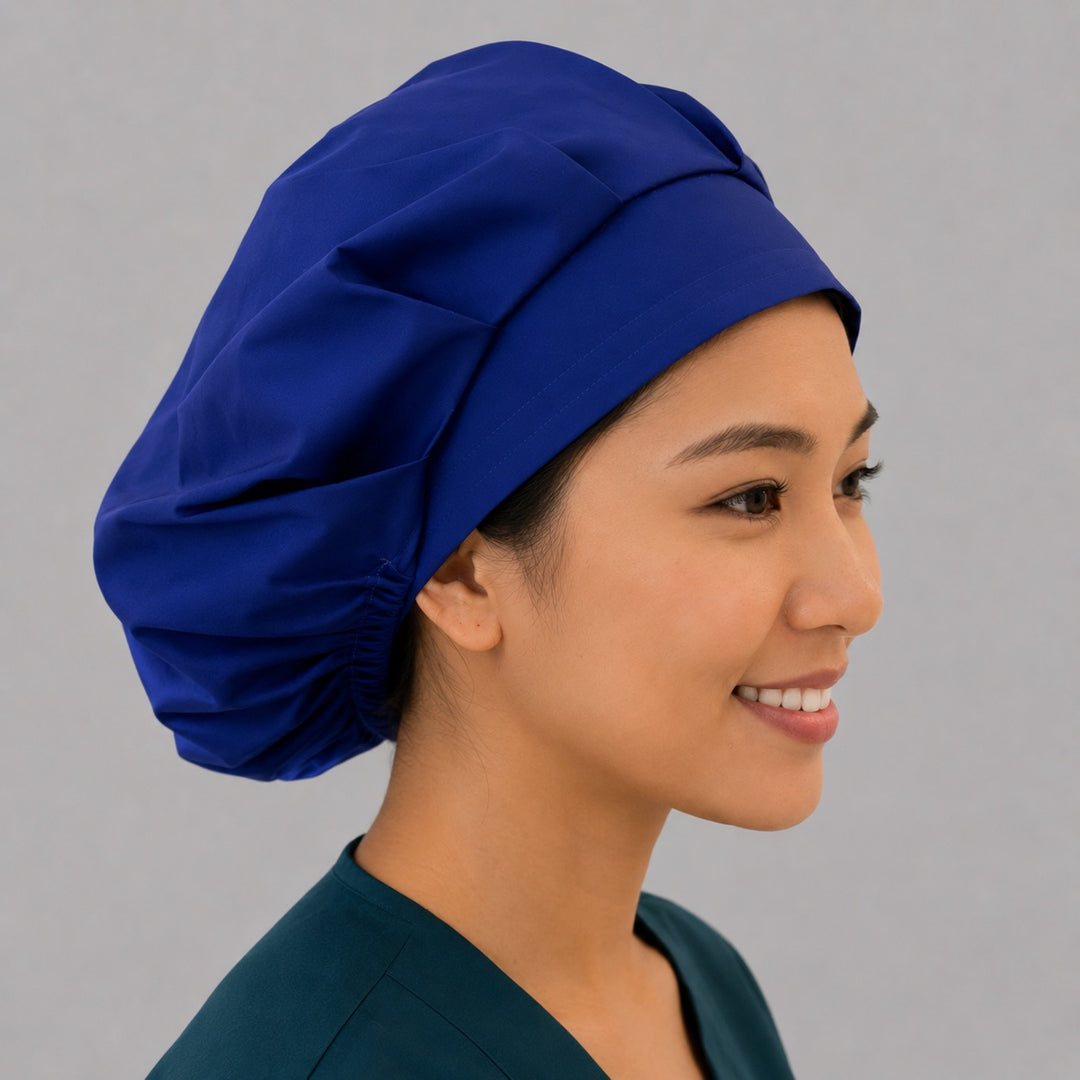 Royal blue bouffant scrub cap right side profile on smiling model showing roomy solid royal blue crown, women&