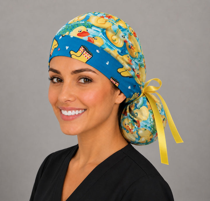 Rubber duckies rain boots ponytail scrub cap right three-quarter angle on smiling model showing yellow ducks, aqua water and yellow rain boot band