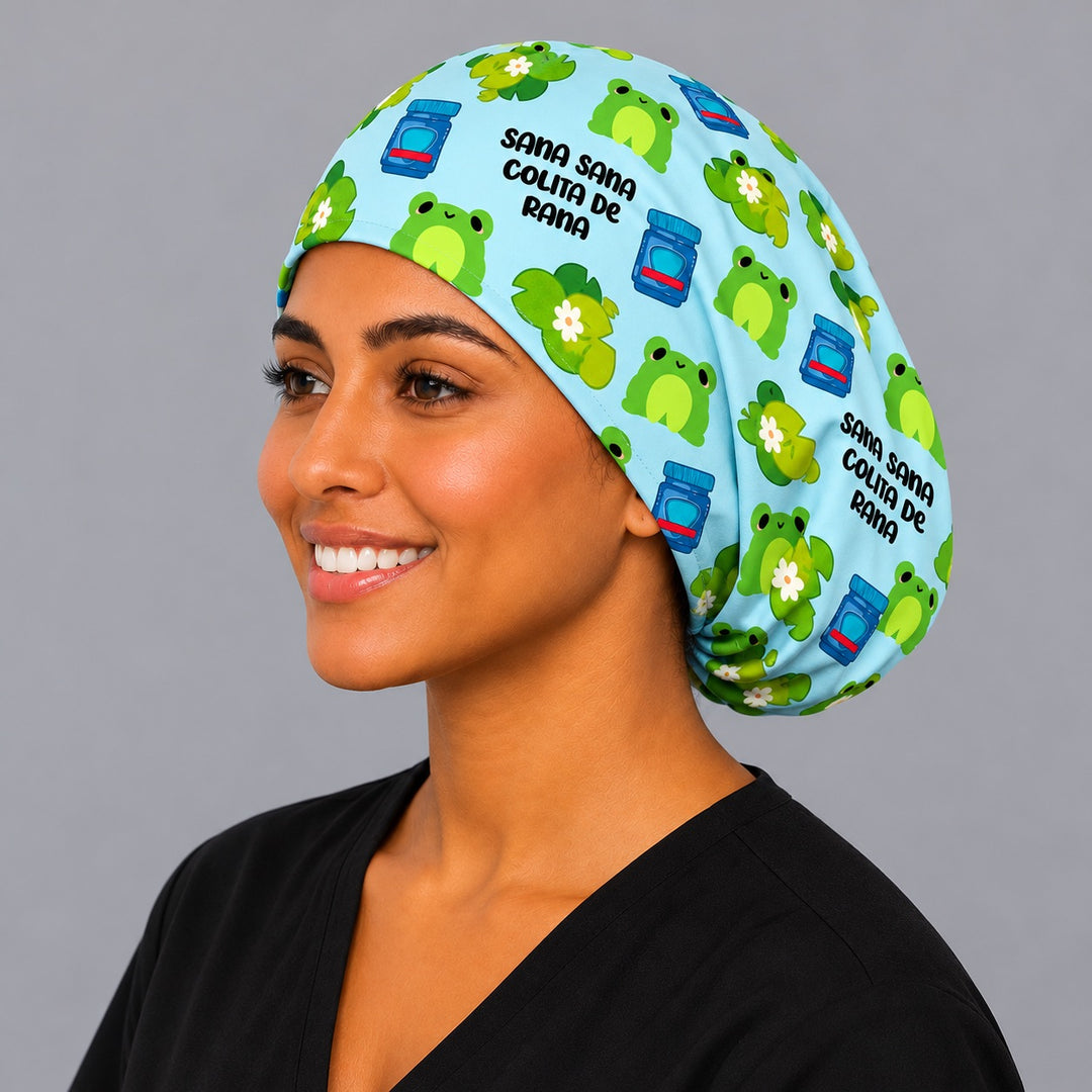 Smiling Latina nurse in a Sana Sana Colita de Rana Euro scrub cap with green frogs and lily pads on sky blue