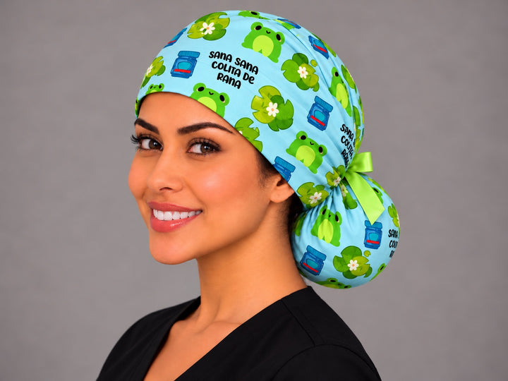 Smiling Latina nurse in a Sana Sana Colita de Rana ponytail scrub cap with lime green bow and frog print