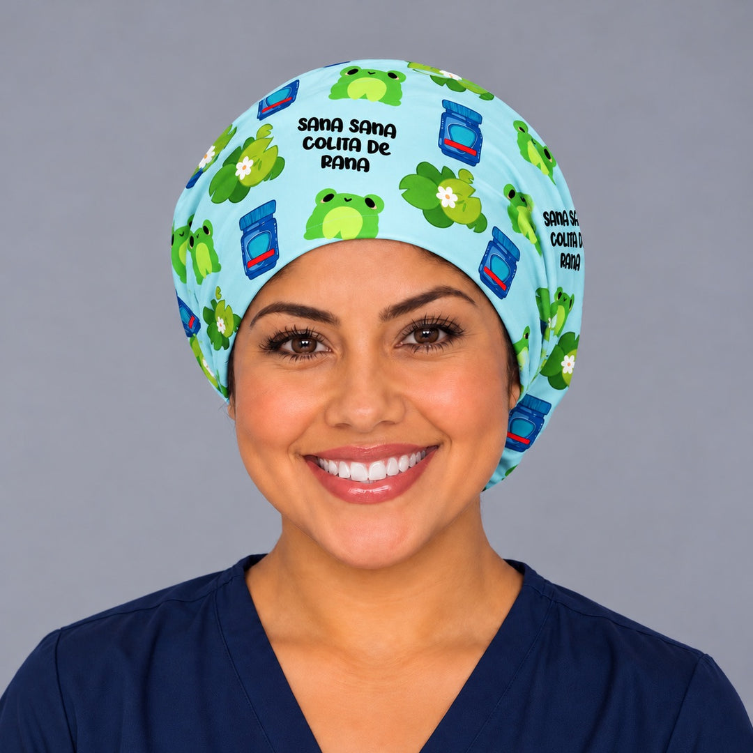 Smiling Latina nurse in navy scrubs wearing the Sana Sana Colita de Rana euro scrub cap, front view with the bold black lettering centered above the forehead