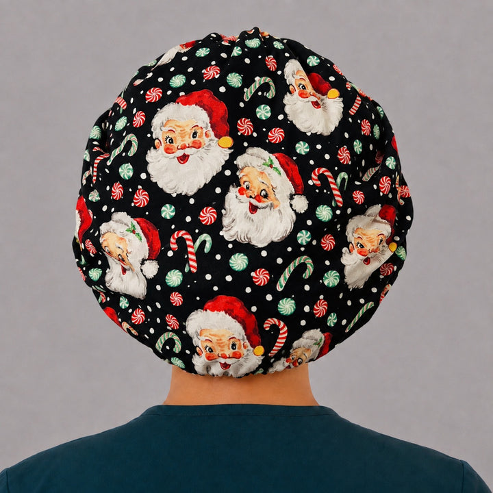 Back view of the Santa bouffant scrub cap — full gathered fit showing Santa faces, peppermints and candy canes on black with snow speckles