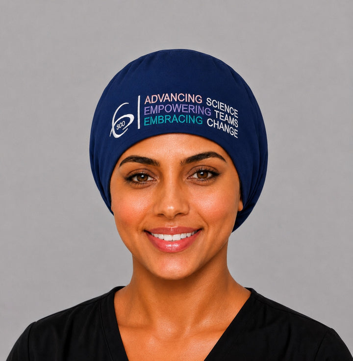 Smiling healthcare professional in a navy SGO official embroidered Euro surgical scrub cap with the full-color Society of Gynecologic Oncology logo and Advancing Science Empowering Teams Embracing Change tagline across the front
