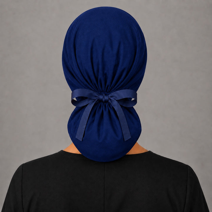 Back view of the navy SGO official ponytail surgical scrub cap showing the roomy pouch and adjustable cotton bow tie that holds long hair and ponytails