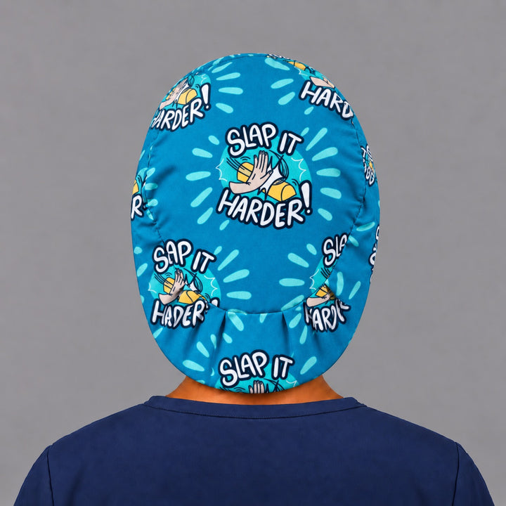 Back view of the Slap It Harder Euro scrub cap — elastic gathered back showing the full comic print
