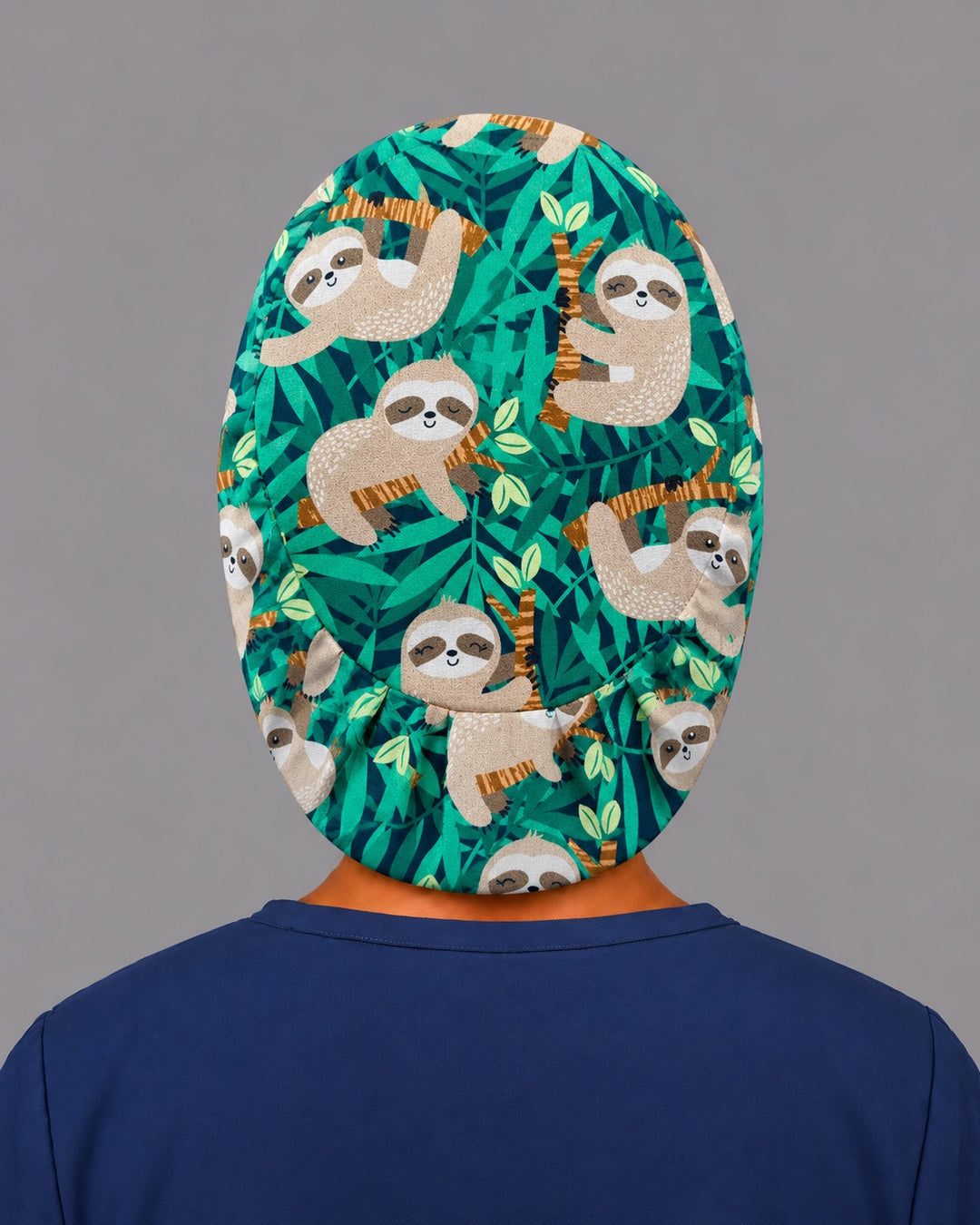 Back view of the sloth Euro scrub cap — elastic gathered back showing sloths and jungle leaves across the green crown