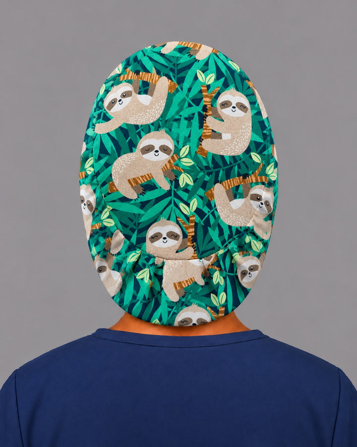 Back view of the sloth Euro scrub cap — elastic gathered back showing sloths and jungle leaves across the green crown
