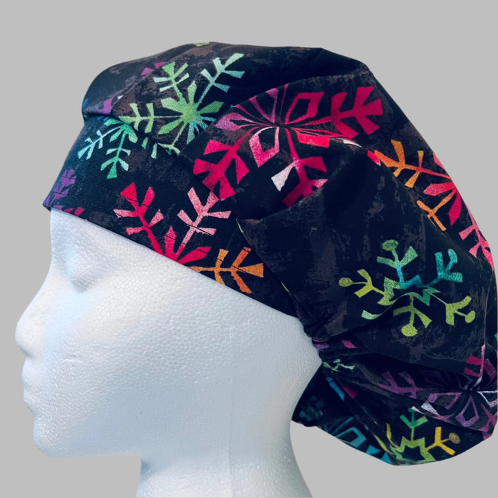 Black bouffant scrub cap with colorful rainbow snowflakes on a model — handmade-in-USA Christmas surgical hat for women from OR World.