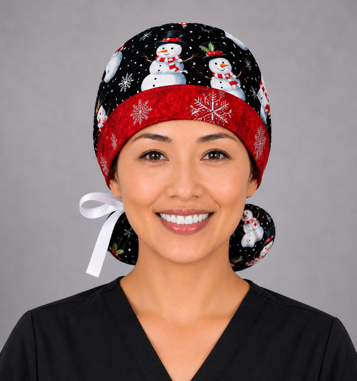 Snowmen ponytail scrub cap left side profile showing gathered ponytail pouch of snowmen in striped scarves on black with red snowflake band and white ribbon tie