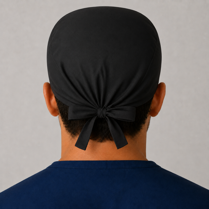Back view of solid black tie-back scrub cap showing the bow tie closure on a male model — handmade-in-USA men&