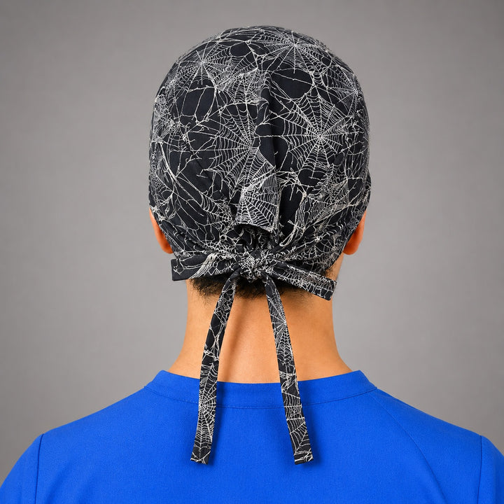 Spider web scrub cap for short hair, handmade black and white cobweb tie-back Halloween surgical hat on OR nurse, front view