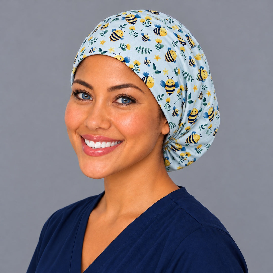 Left three-quarter angle of a smiling healthcare worker in a spring bee print euro cap, with close detail of the striped bees and blue wings at print scale