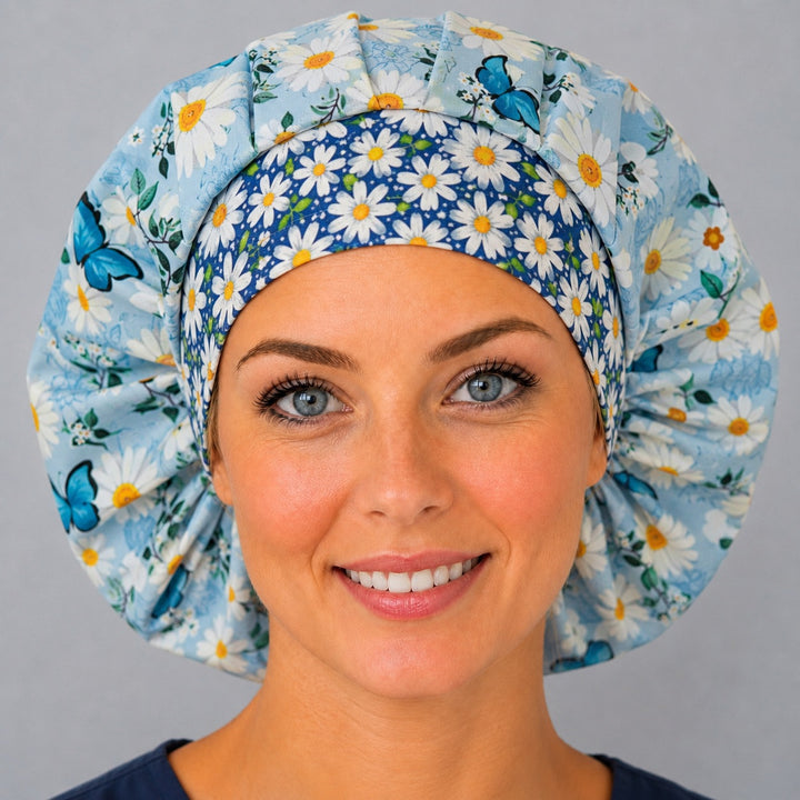 Woman wearing a spring floral butterfly bouffant scrub cap, front view — blue daisy floral print with butterflies and navy daisy band, adjustable women&