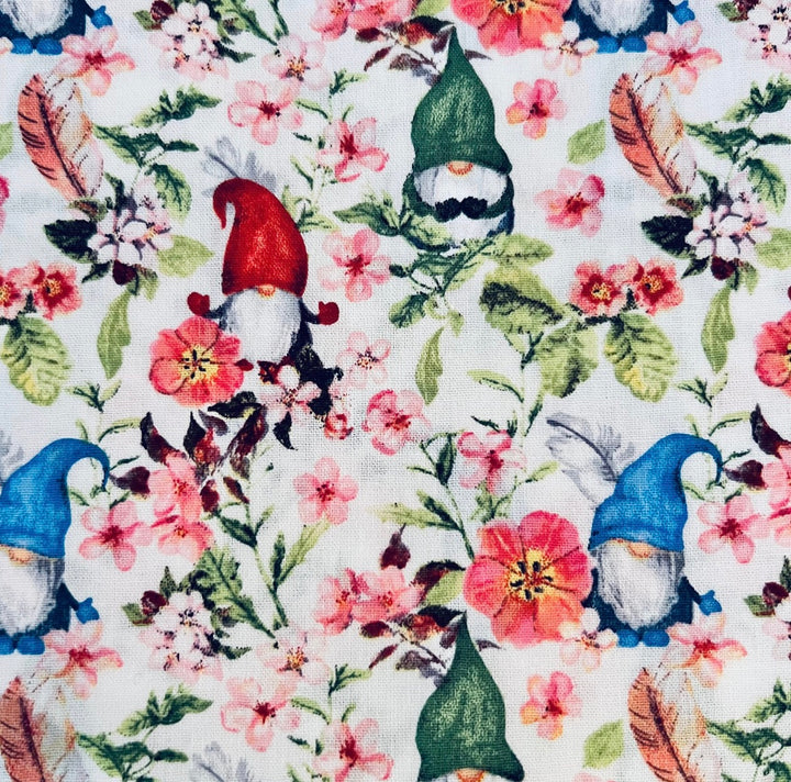Fabric detail of the spring gnome scrub cap — close-up of gnomes, pink blossoms and feathers on white cotton
