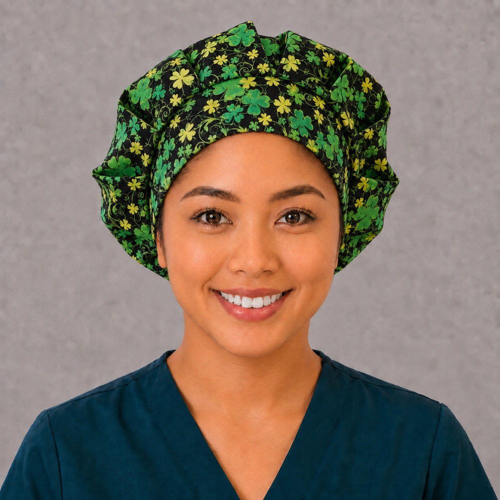 Woman wearing a St. Patrick's Day clover bouffant scrub cap, front view — glittering green four-leaf clovers on black, adjustable women's surgical hat