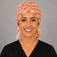 Front view of coral stork ponytail scrub cap on L&D nurse, labor and delivery surgical hat for women, handmade USA, OR World