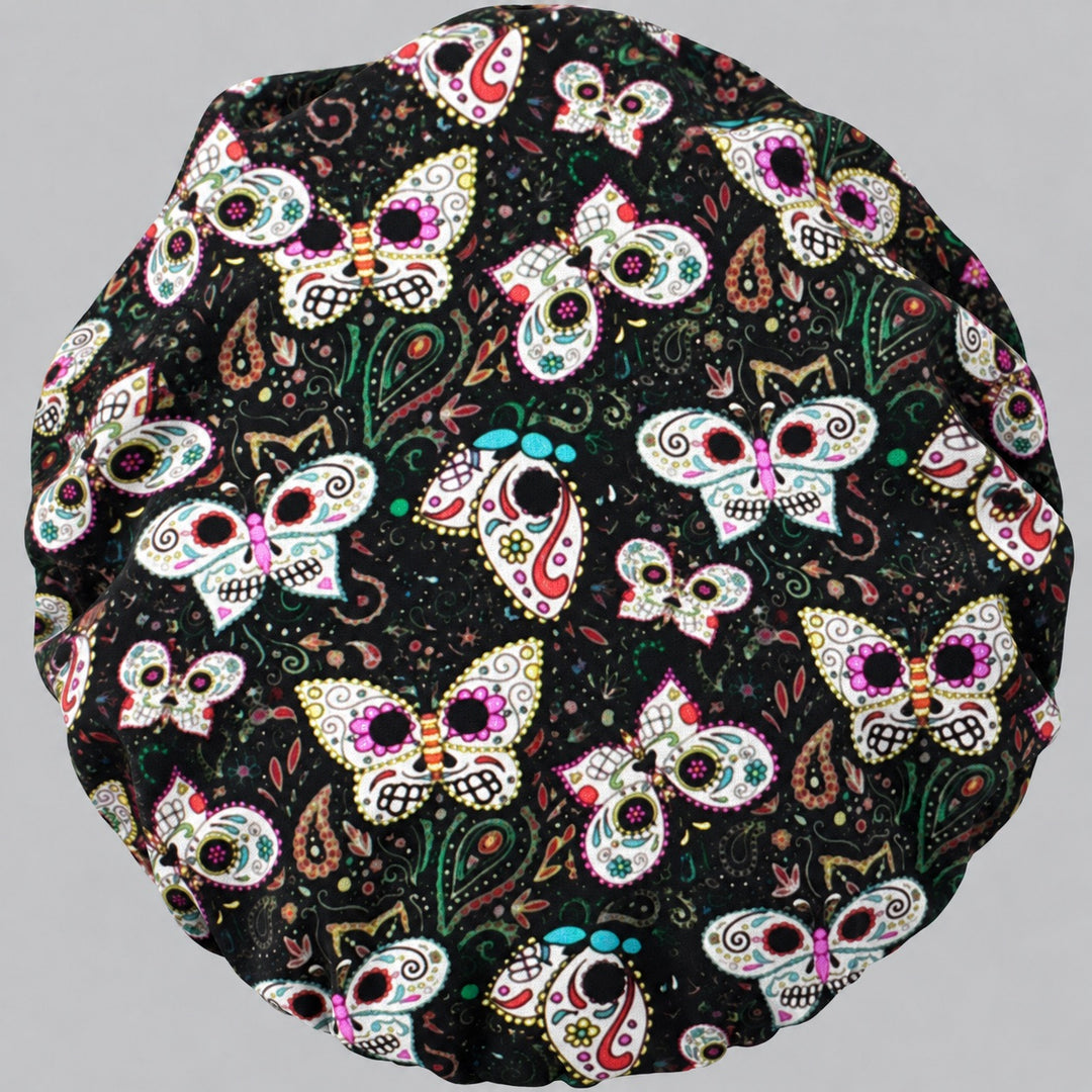 Sugar Skull Butterfly bouffant scrub cap, flat lay view — Día de los Muertos butterflies on black paisley fabric