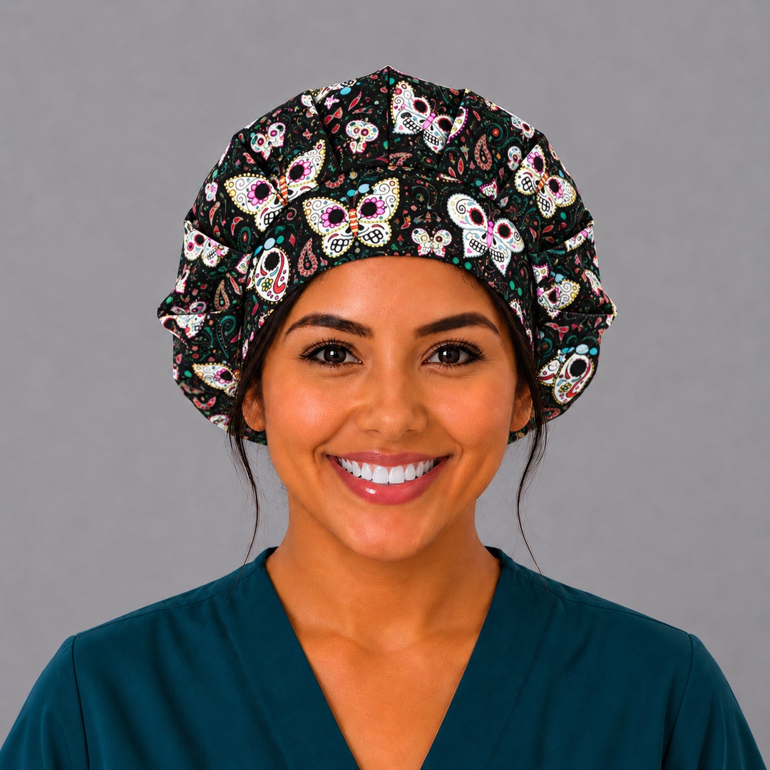 Woman wearing a Sugar Skull Butterfly bouffant scrub cap, front smiling view — painted skull butterflies on black, roomy gathered surgical hat