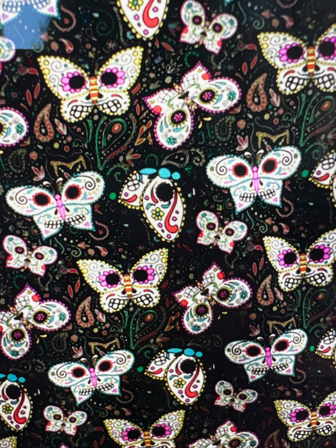 Fabric detail of the Sugar Skull Butterfly scrub cap — close-up of painted skull butterflies and paisley on black cotton