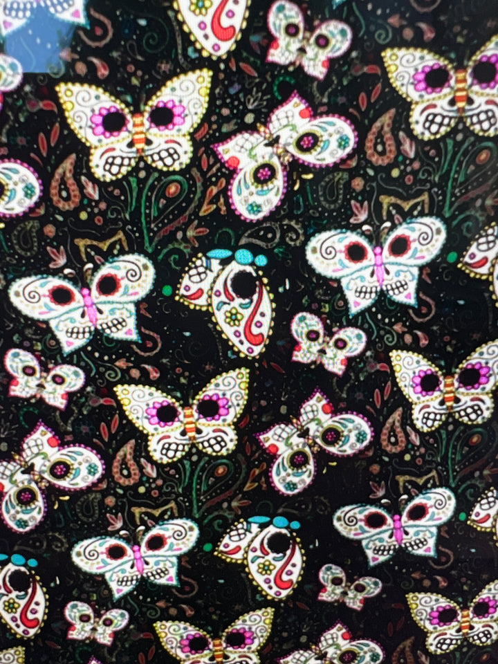Fabric detail of the Sugar Skull Butterfly scrub cap — close-up of painted skull butterflies and paisley on black cotton