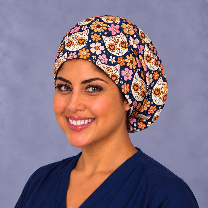 Sugar skull cat Euro surgical hat, left three-quarter view, unisex Día de los Muertos scrub cap with pink and orange retro blooms