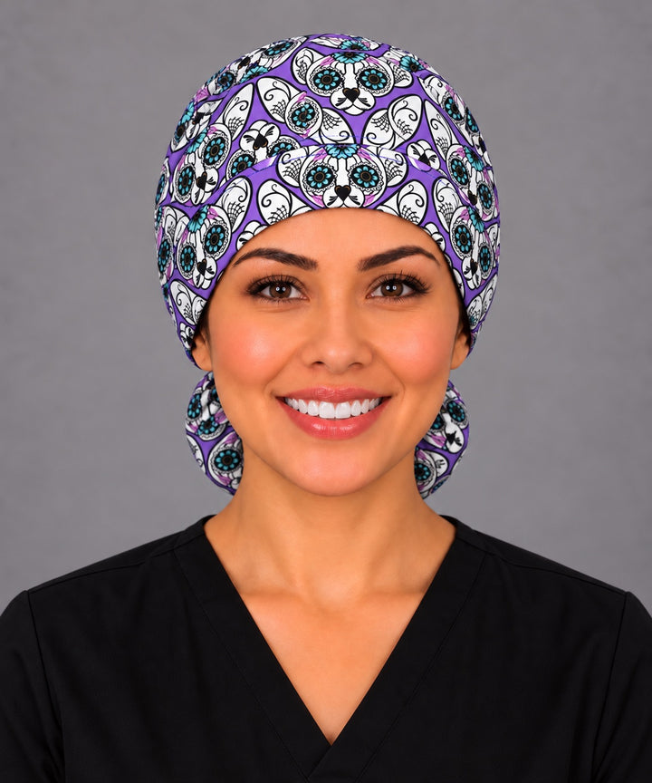 Woman wearing a purple sugar skull cat ponytail scrub cap, front view — calavera cats with teal flower eyes, Mexican surgical hat for long hair