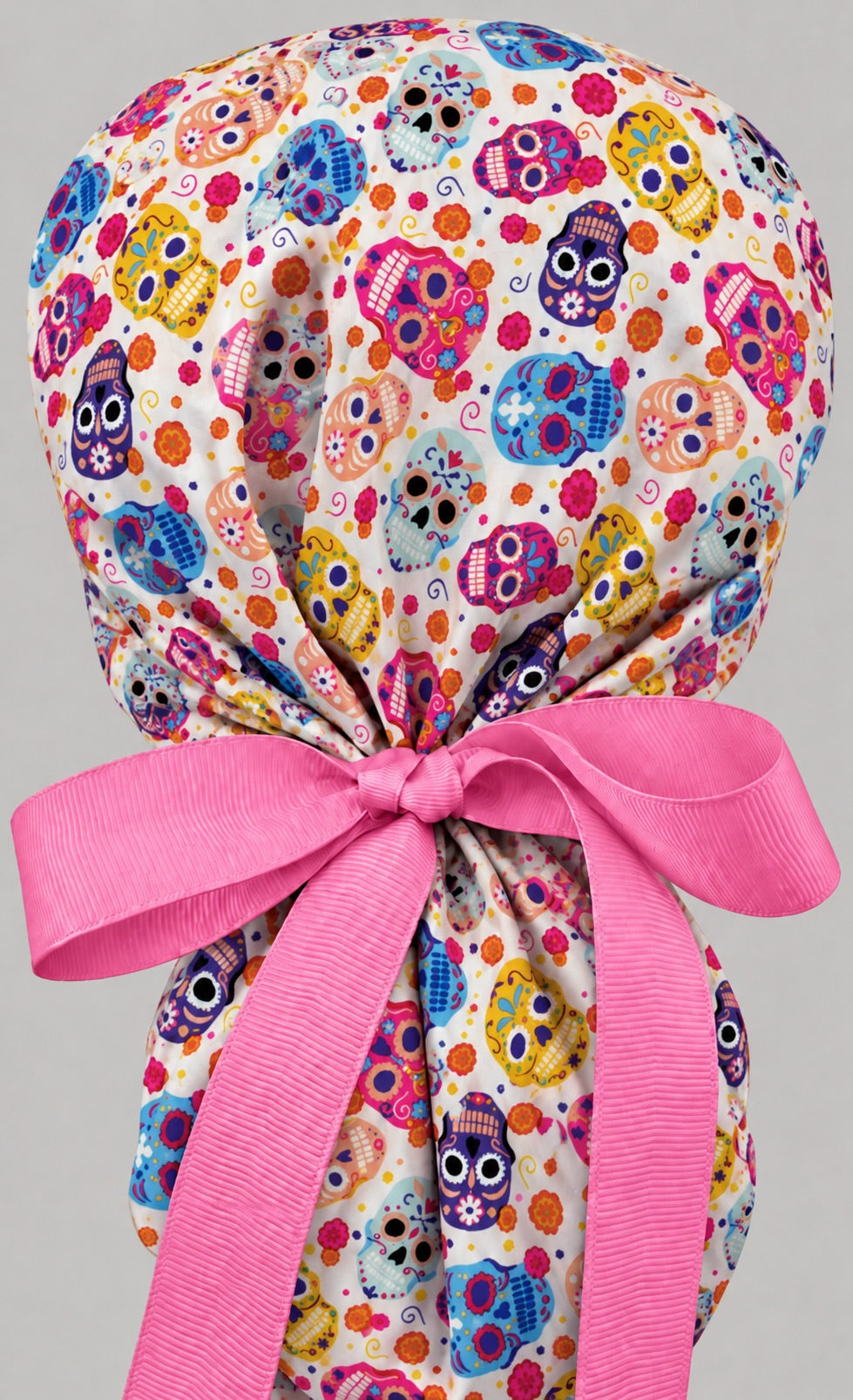 Back view of the sugar skull ponytail cap, showing the gathered crown and long hot pink grosgrain ribbon tails tied in a wide bow