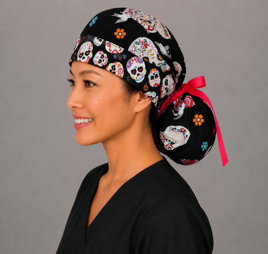 Sugar skull ponytail scrub cap right side view showing gathered ponytail pouch full of colorful floral sugar skulls, roses and birds on black with pink ribbon bow