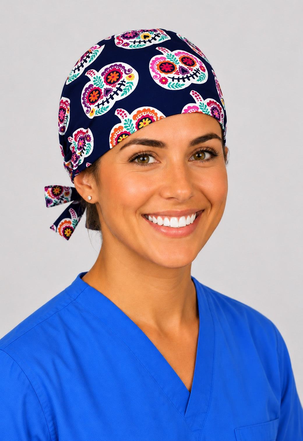 Nurse wearing sugar skull pumpkin tie back scrub cap, navy Day of the Dead calavera surgical hat by OR World