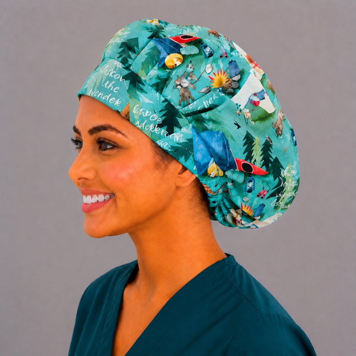 Summer camping bouffant scrub cap left side profile showing teal woodland print with tents, kayaks and pine trees, women&