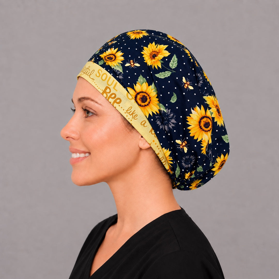 Woman wearing a sunflower and bee Euro scrub cap, front view — navy print with a yellow Bee Grateful band, adjustable surgical hat