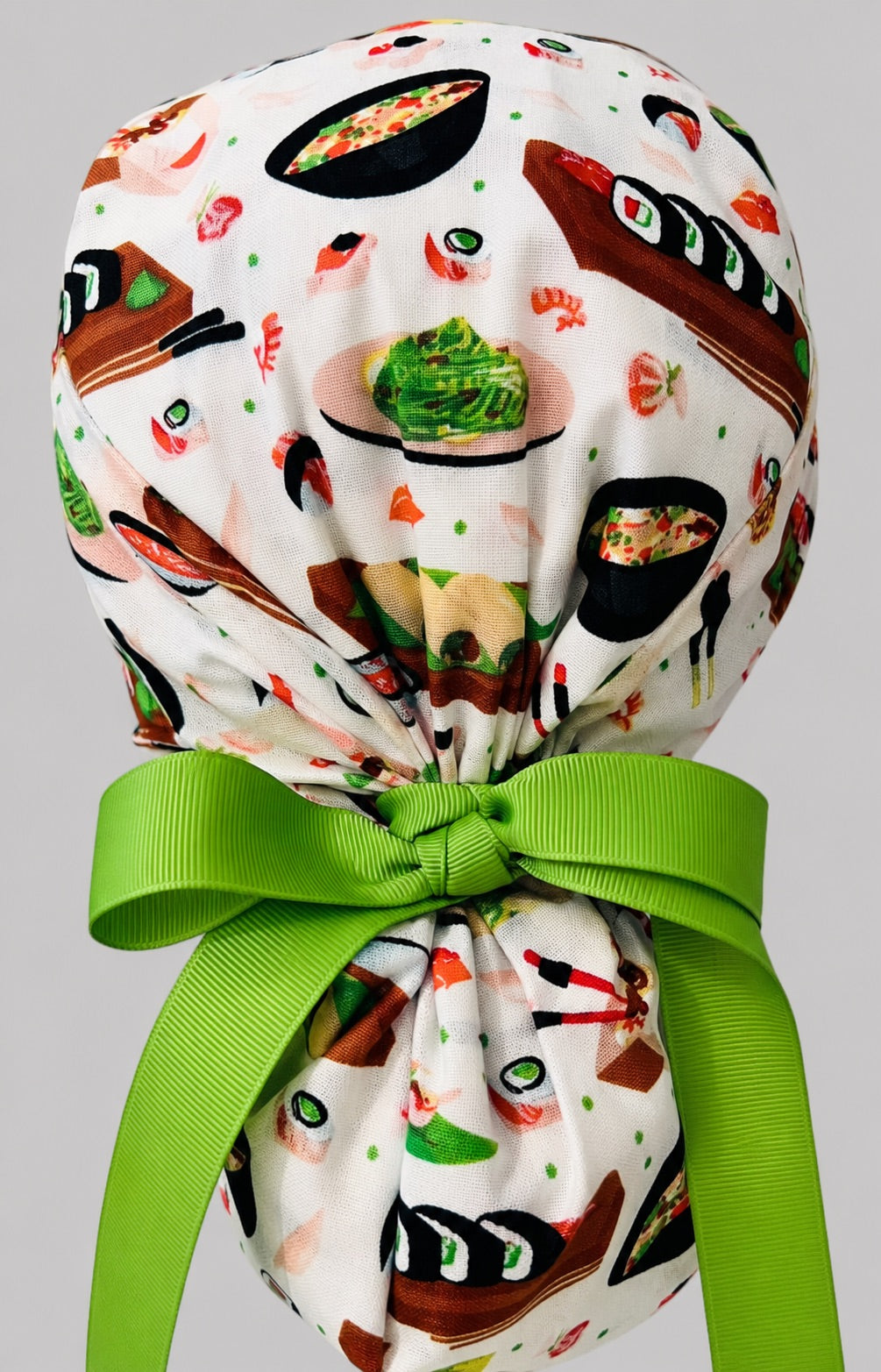 Sushi ponytail scrub cap back view close-up showing gathered pouch full of sushi rolls, ramen bowls, edamame and lime green ribbon bow