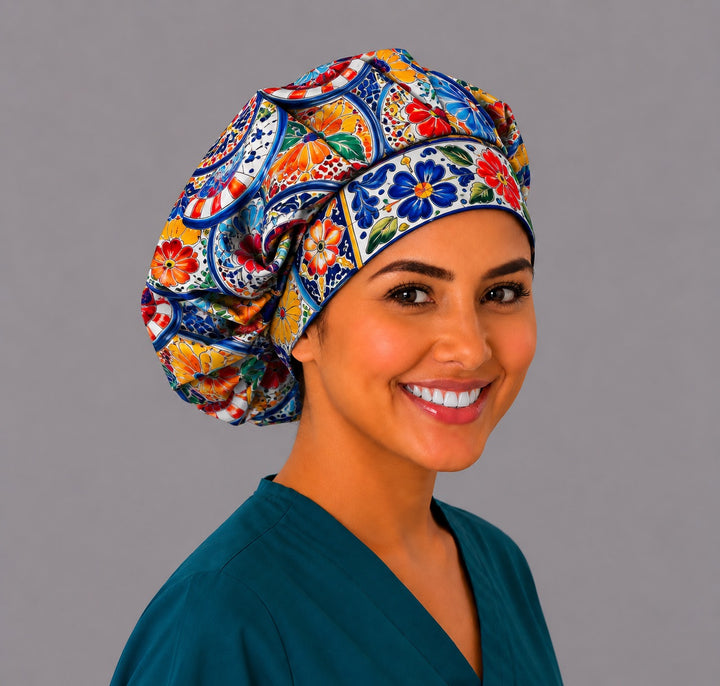 Smiling nurse in an original Talavera tile bouffant scrub cap with cobalt blue borders and red and marigold Mexican flowers