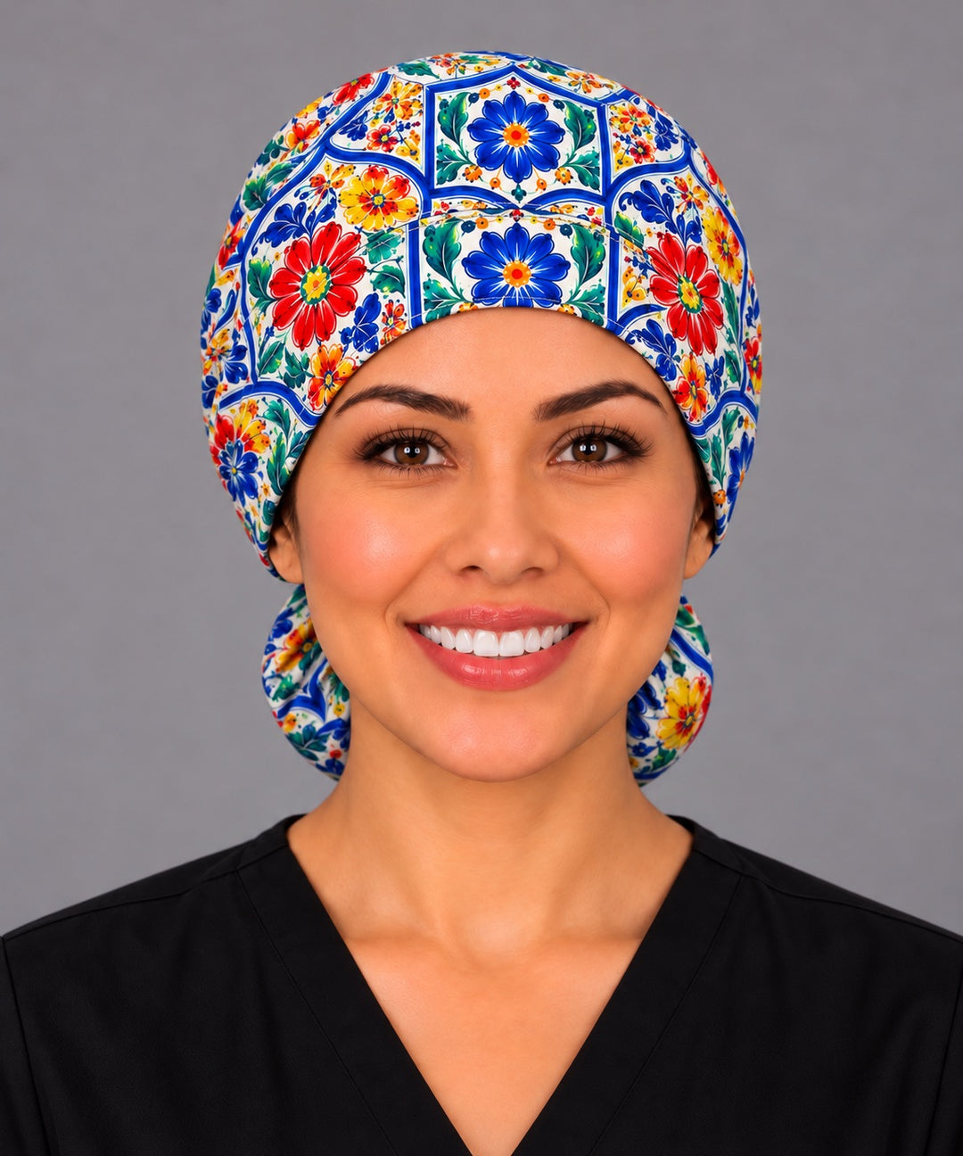 Smiling nurse in black scrubs wearing a Talavera tile ponytail scrub cap, front view of the cobalt blue framed floral band sitting smoothly across the forehead