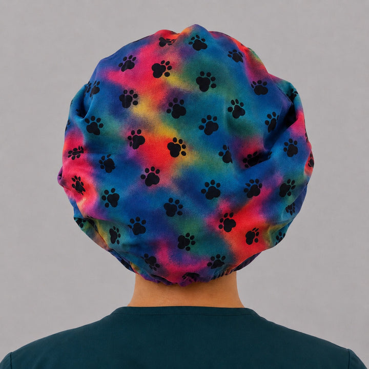 Back view of the tie-dye paw print bouffant scrub cap — full gathered coverage showing black paws across the rainbow crown
