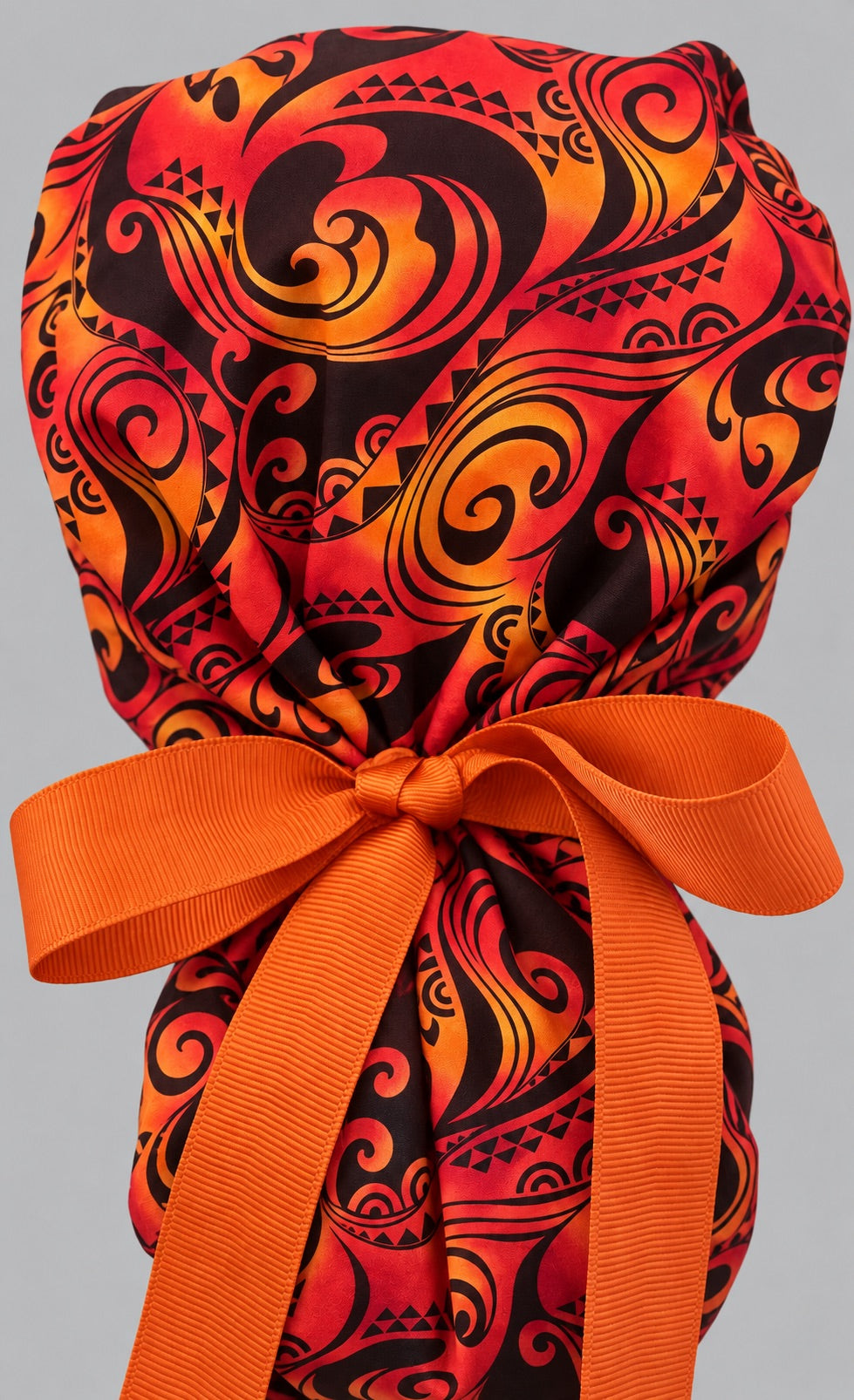 Back view of the Tribal Fire ponytail scrub cap — close-up of the orange grosgrain ribbon bow gathering the ponytail pouf