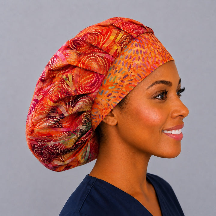Tropical batik bouffant scrub cap, right side profile — coral and tangerine print with room for long thick hair