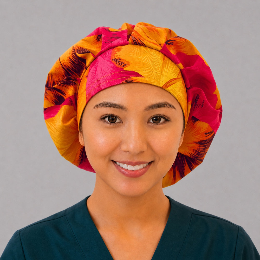 Tropical Hawaiian hibiscus bouffant scrub cap left three-quarter angle on smiling model showing hot pink and orange hibiscus flowers, women&