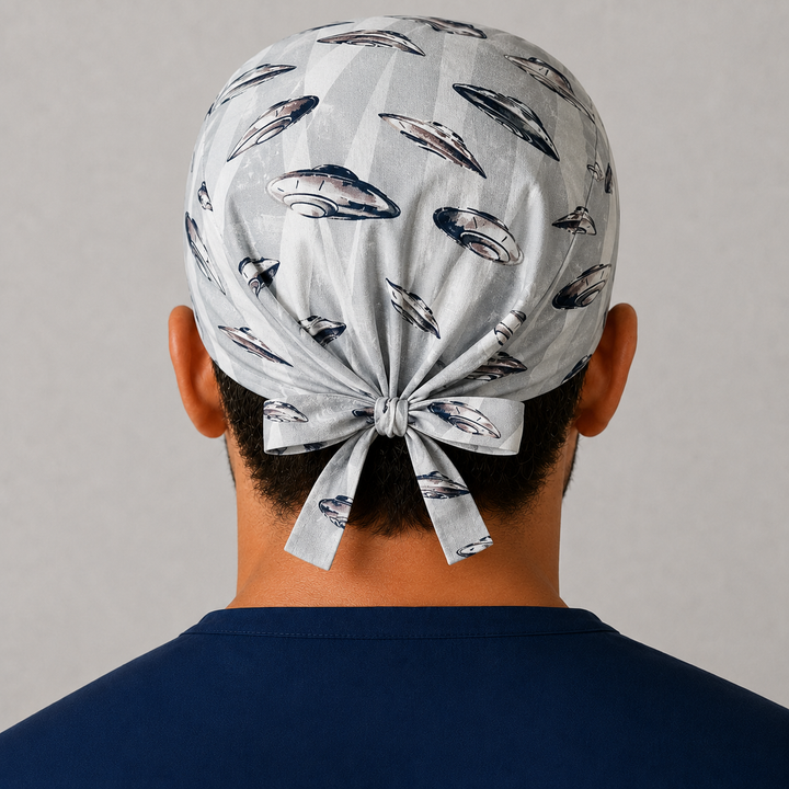 Back view of UFO &amp; spaceships tie-back scrub cap showing the bow tie closure on a male model — handmade-in-USA OR World surgical hat.