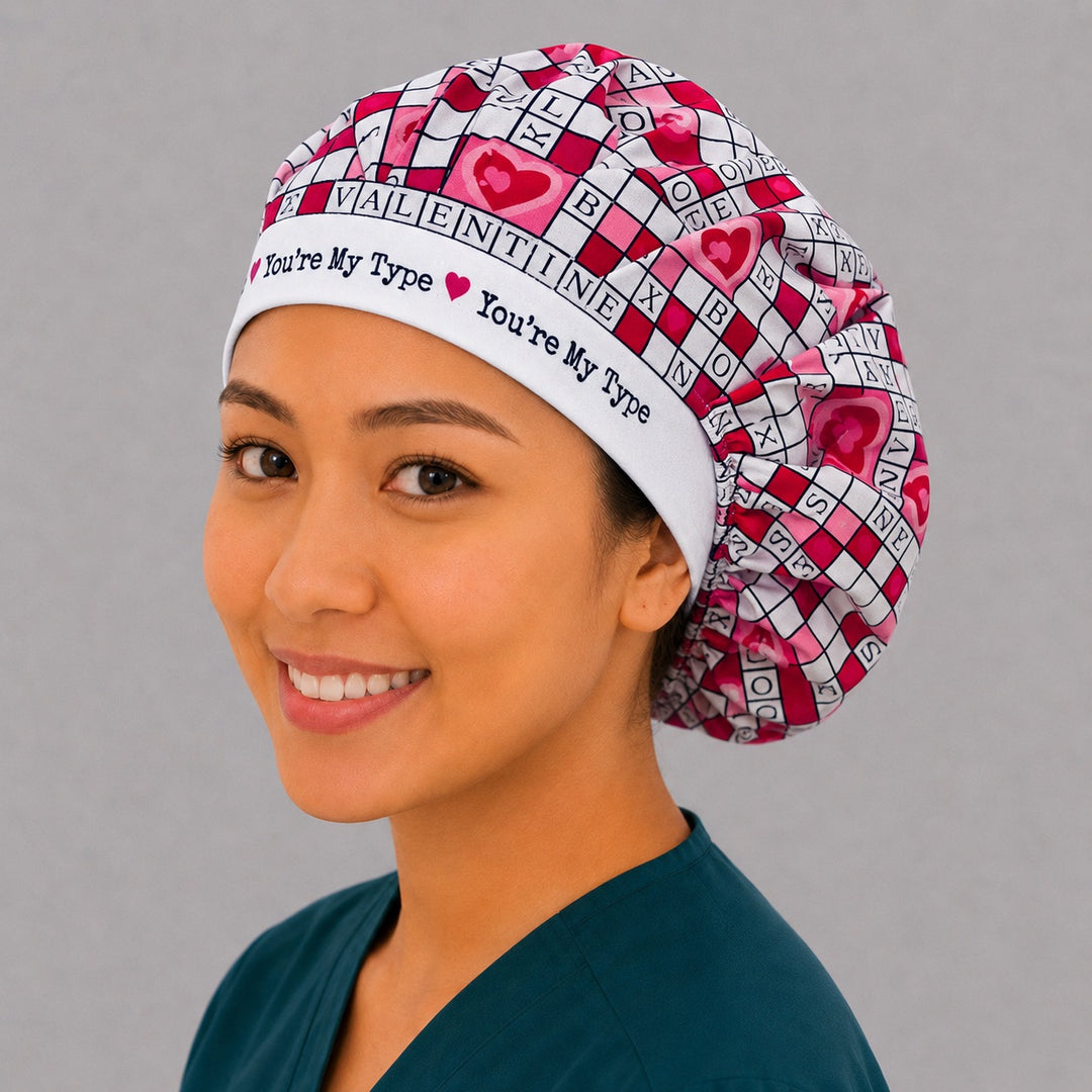 Woman wearing a Valentine crossword bouffant scrub cap — white crossword and heart print with a You're My Type lettered band, adjustable women's surgical hat
