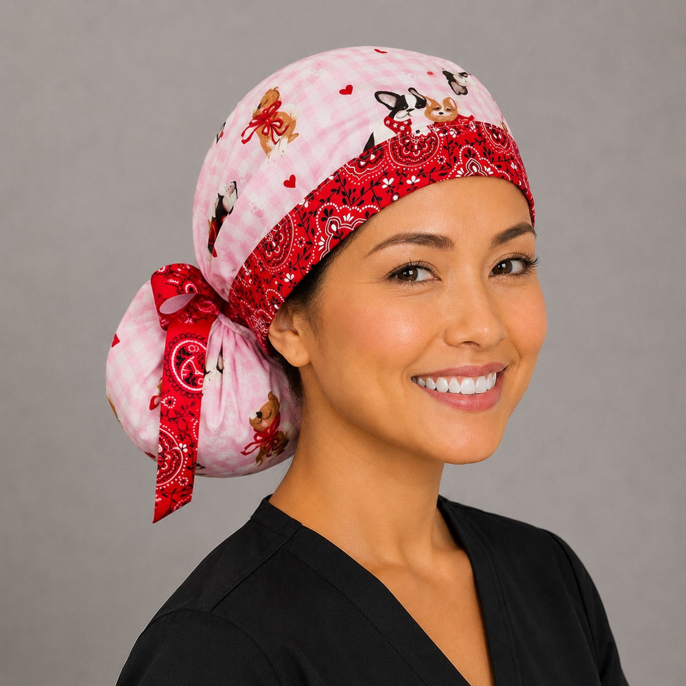 Valentine dogs ponytail surgical cap left side profile showing gathered ponytail pouch of puppies, hearts and bows on pink gingham with red bandana ribbon tie