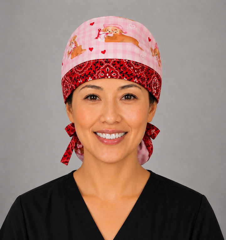 Valentine dogs ponytail nurse cap left three-quarter angle on smiling model showing puppies, hearts and bows on pink gingham with red bandana band and red ribbon bow