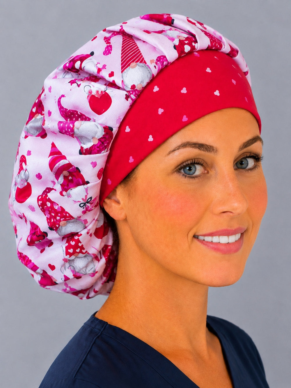 Woman wearing a Valentine gnome bouffant scrub cap, front view — pink and red gnomes with hearts and a red mini-heart band, adjustable women's surgical hat