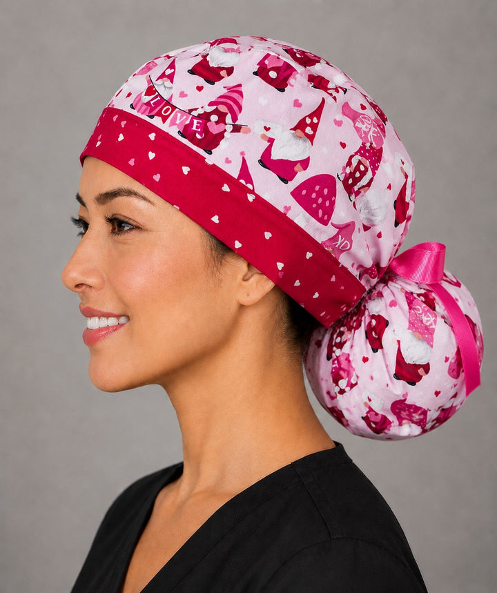 Valentine gnomes ponytail surgical cap right three-quarter angle showing red and pink gnomes and hearts on pink with red heart band and pink ribbon bow