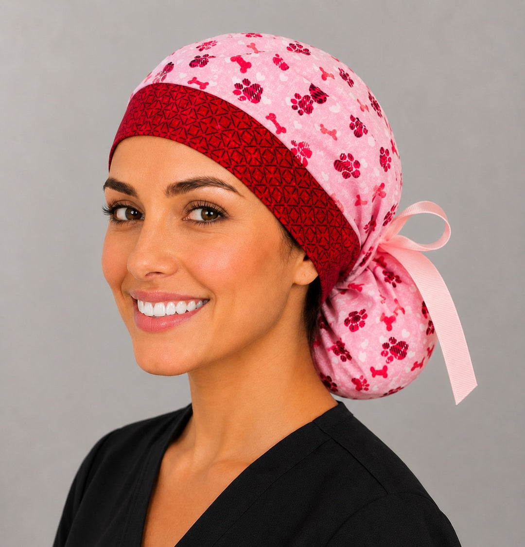 Valentine puppy paws and bones ponytail scrub cap back view close-up showing gathered pouch full of pink and red paw prints, dog bones and hearts with pink grosgrain ribbon bow